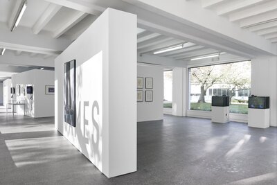 Hall with white walls with pictures, in the background 2 televisions.