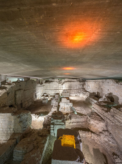 Blick von einer Plattform auf antike Mauern und Gänge im Keller eines Hauses