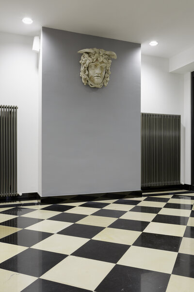 The sculpture of a Medusa hangs on a wall