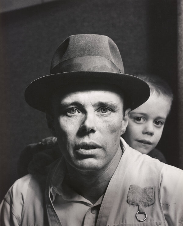 Foto von Joseph Beuys mit einem Klinkind im Hintergrund.