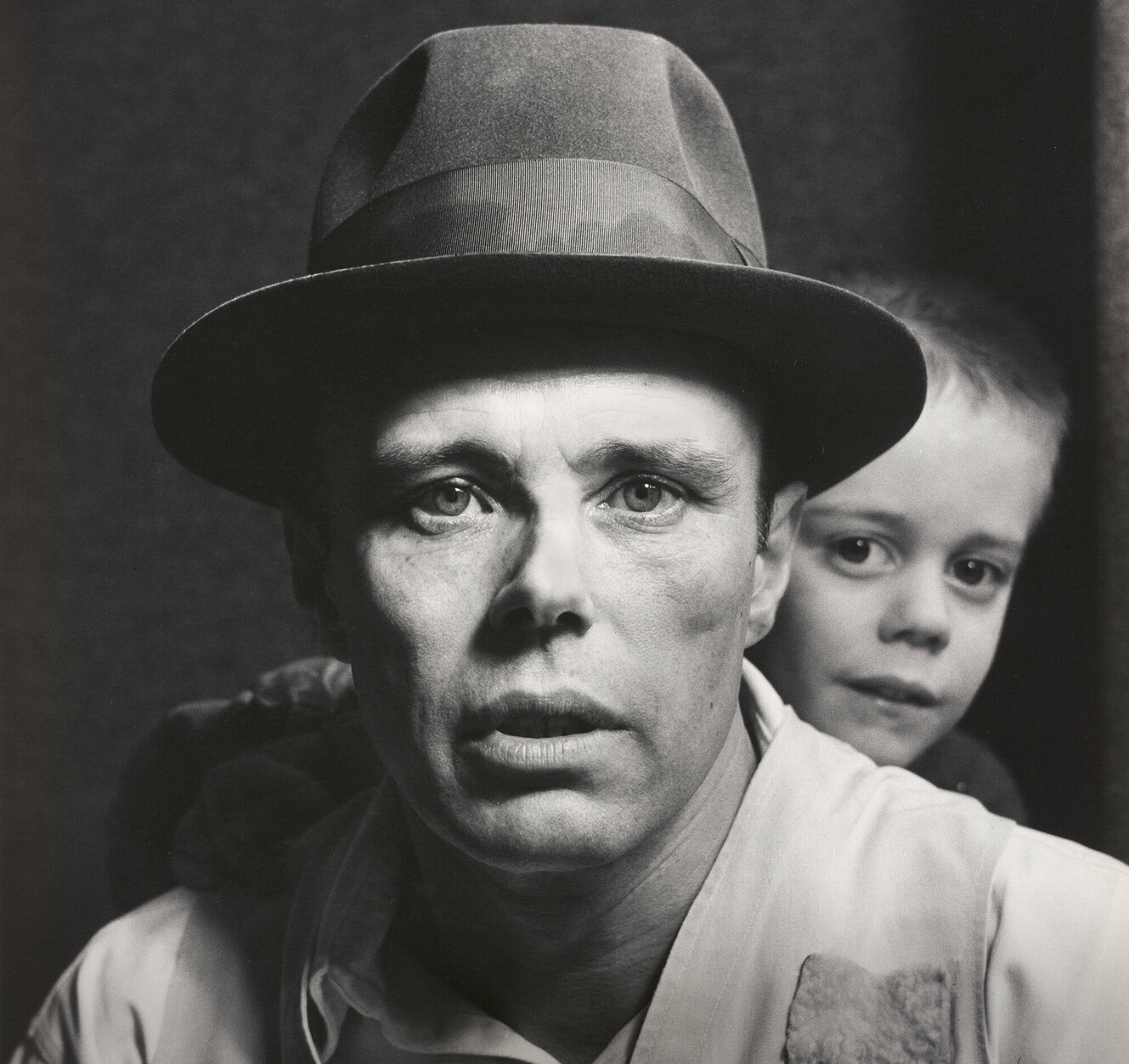Foto von Joseph Beuys mit einem Klinkind im Hintergrund.