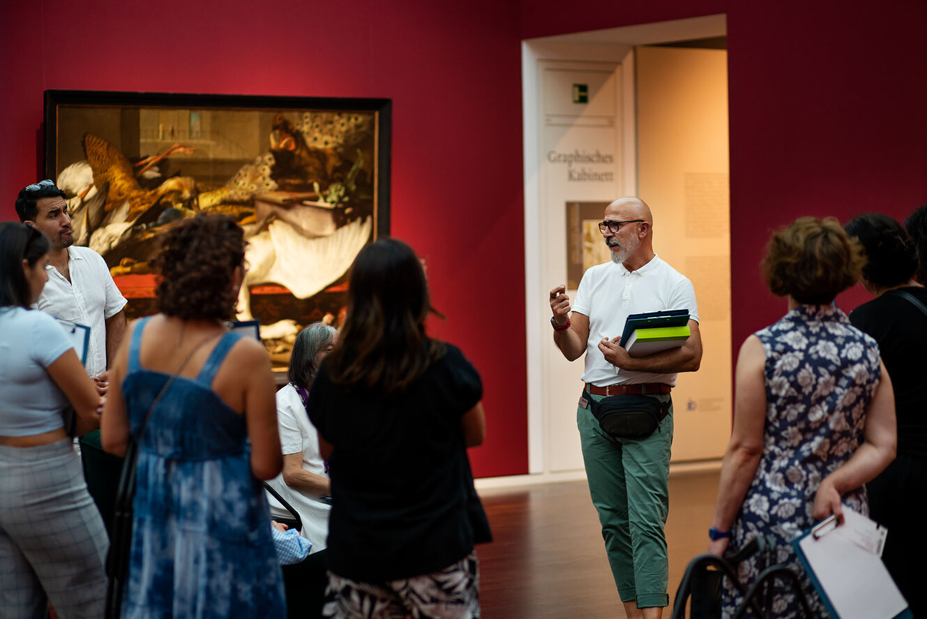 Ein Mann führt eine Gruppe Menschen durch ein Museum