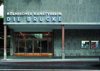 House with an entrance with glass doors, above it a neon sign: Kölnischer Kunstverein, Die Brücke.