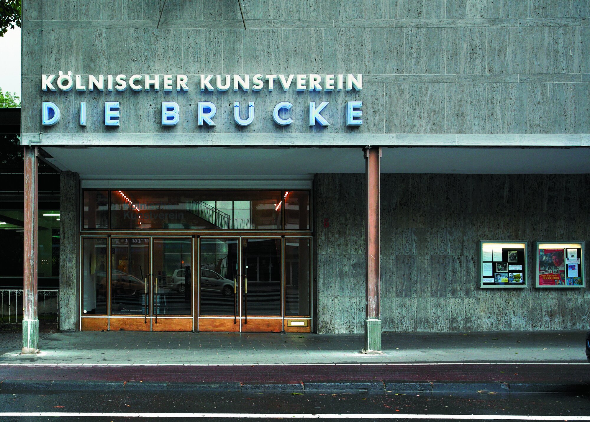 Haus mit einem Eingang mit Glastüren, darüber eine Leuchtschrift: Kölnischer Kunstverein, Die Brücke