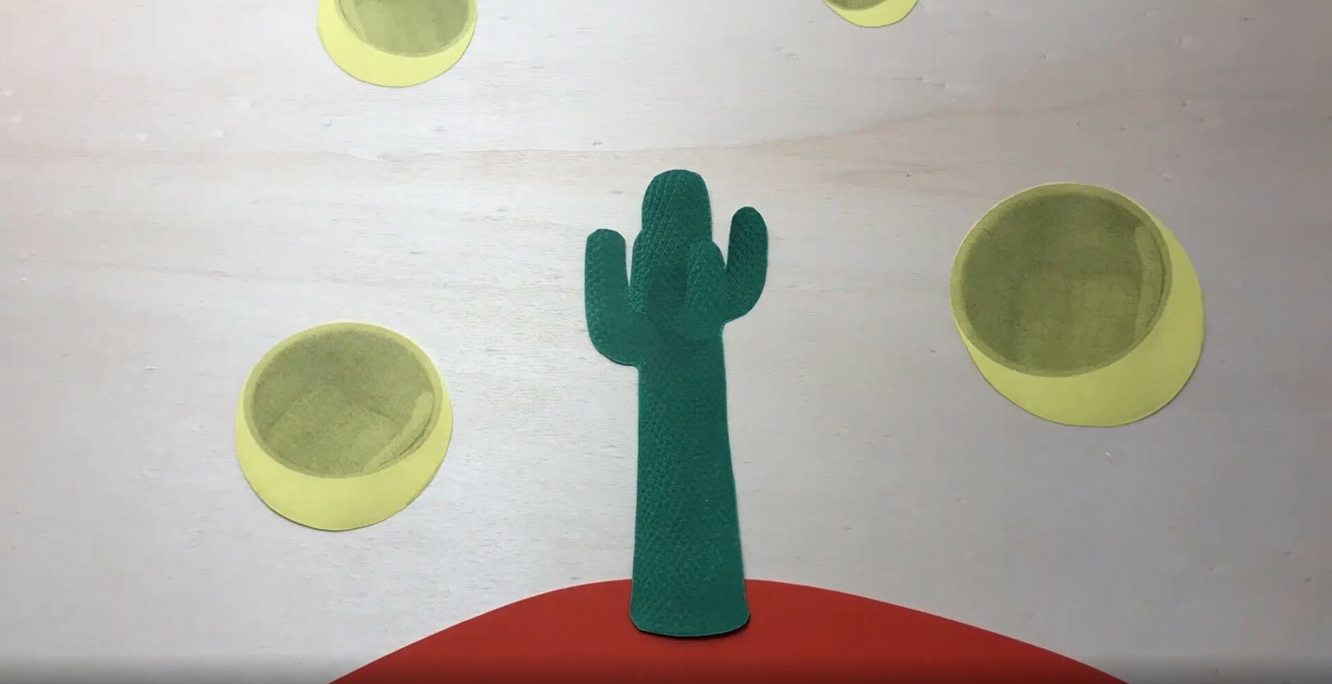 Ein Kaktus steht auf einem kleinen Hügel umgeben von gelben Kugeln