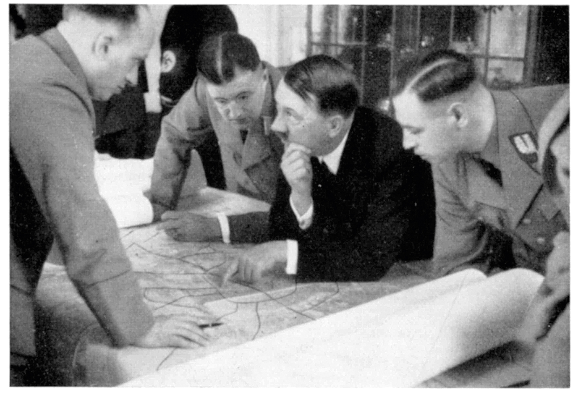 Adolf Hitler und weitere Personen über eine Karte gebeugt