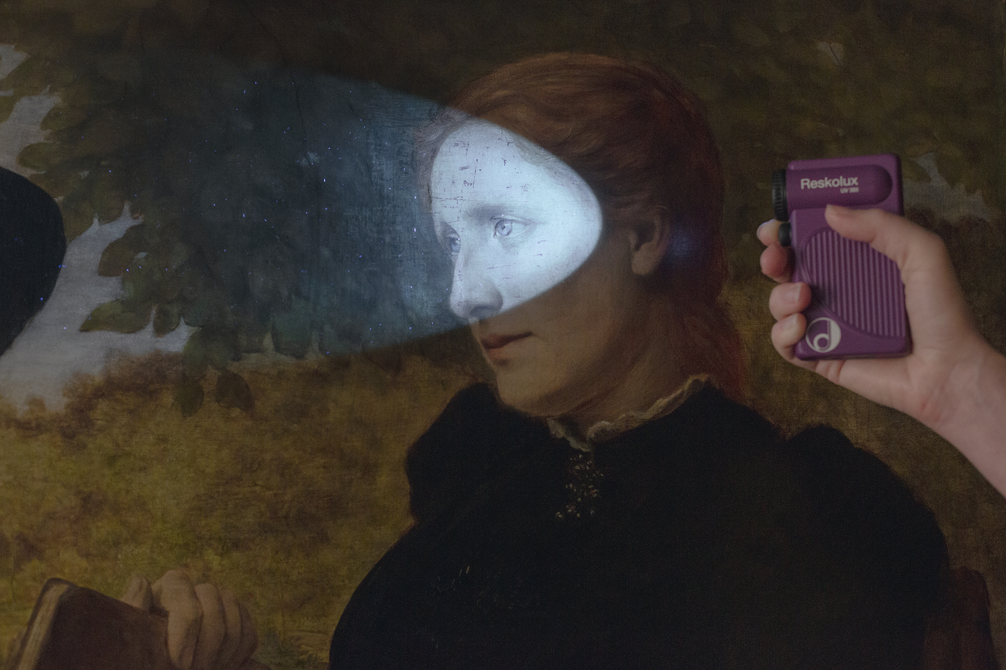 Detailaufnahme eines gemalten Frauenporträts, das zur Untersuchung mit der Handlampe beleuchtet wird. 